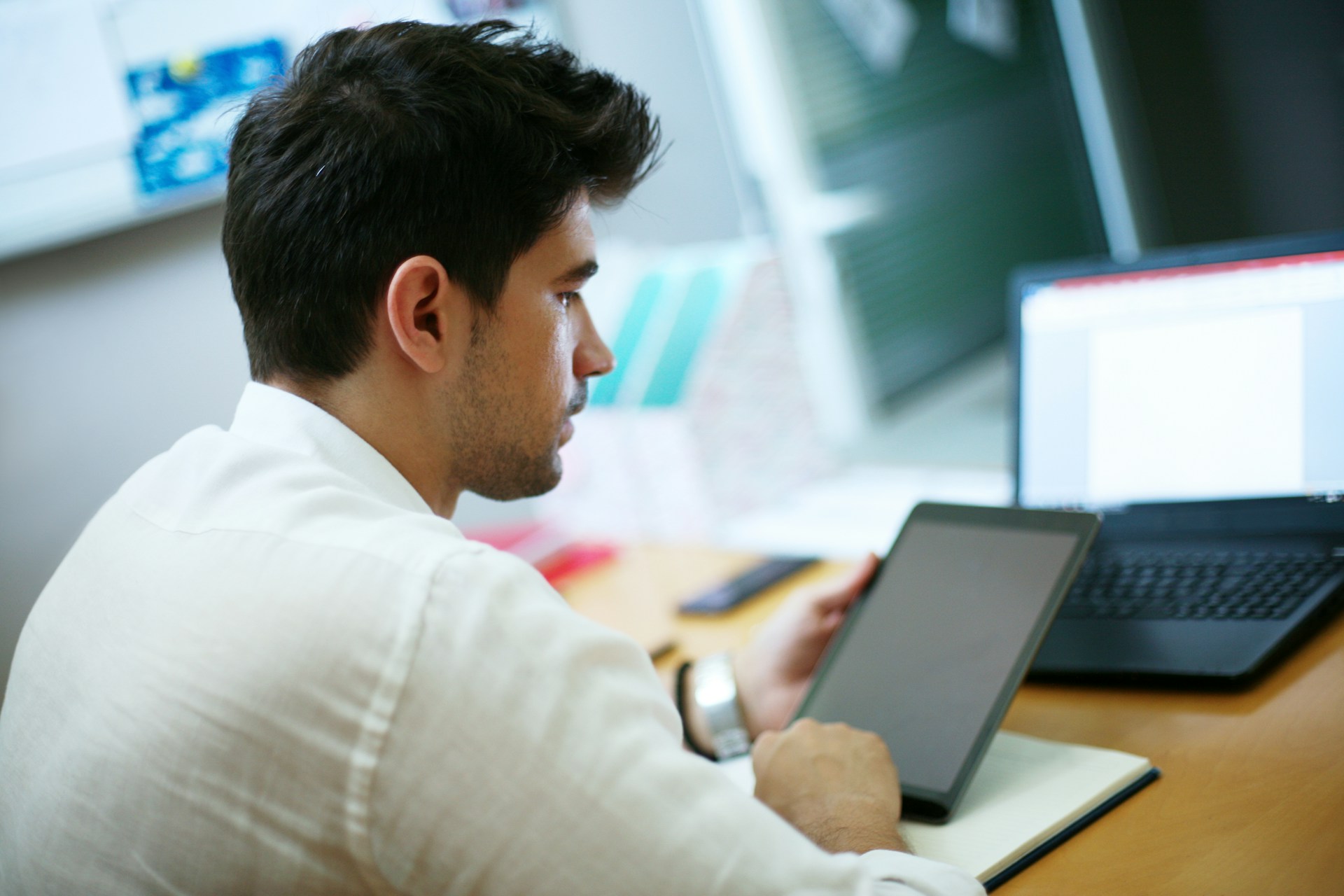 An operator working between a tablet and a laptop — the everyday rhythm of an automated claims workflow.