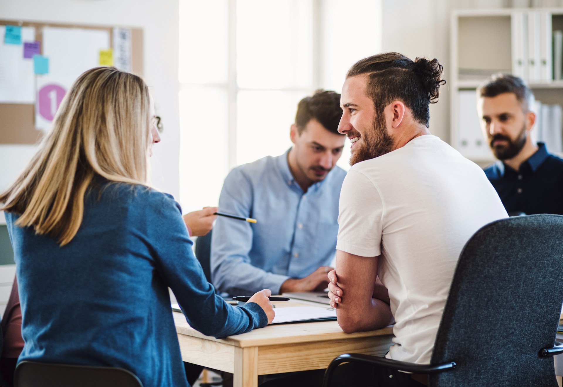 Founders in conversation — a small team meeting around a desk in a bright office.